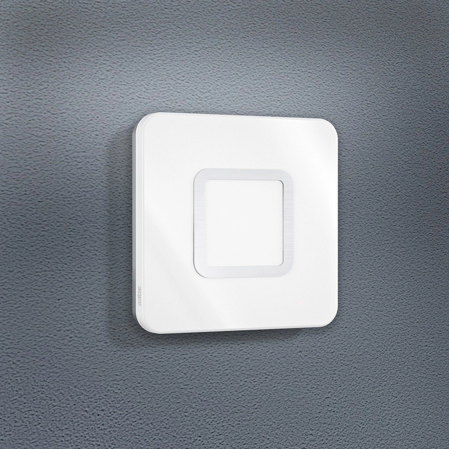 Quadratische Steinel LED-Deckenleuchte RS LED M1 S Edelstahl mit Bewegungsmelder an grauer Wand.