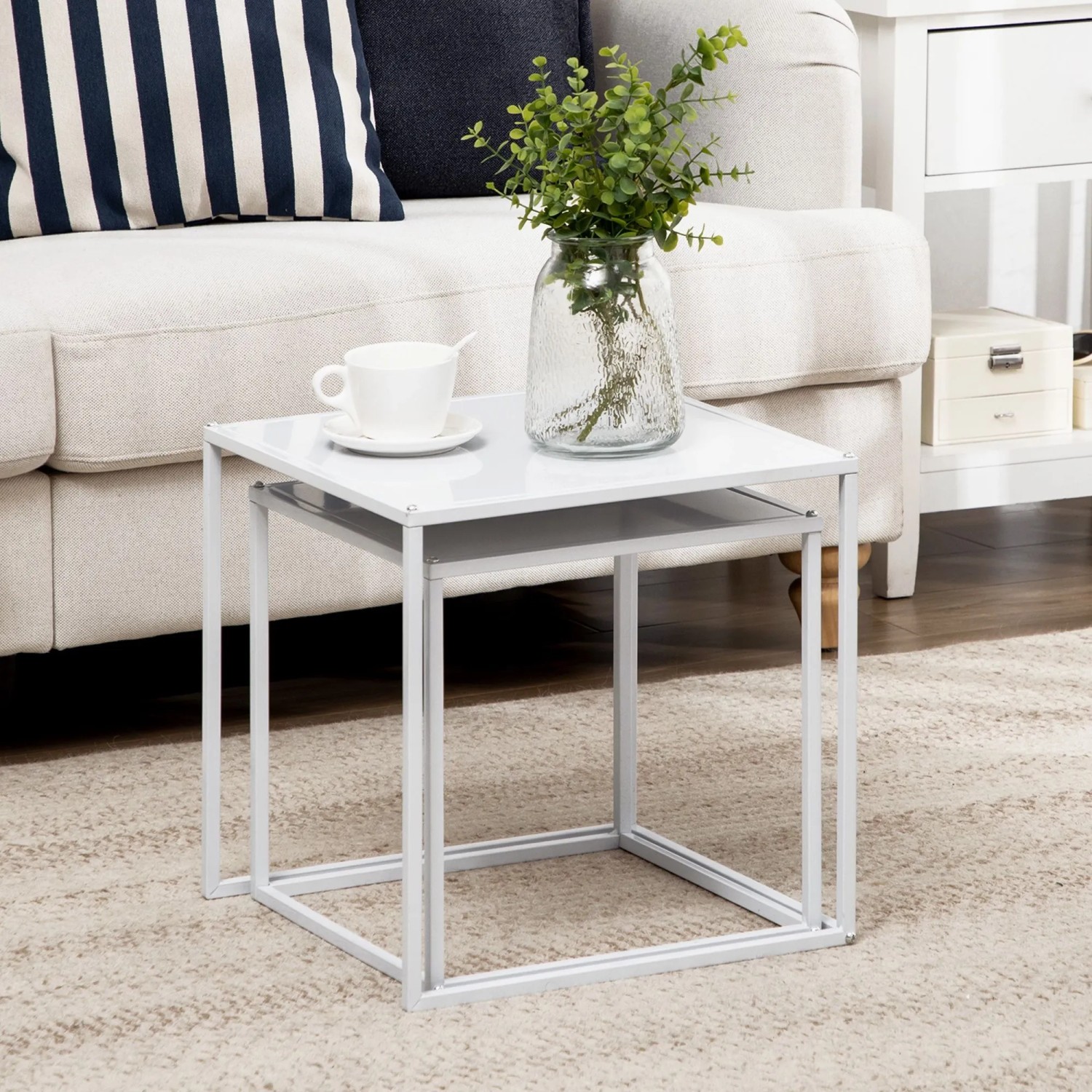 HOMCOM Couchtisch-Set: zwei weiße Stahl-Beistelltische, ineinandergeschoben, mit Deko im modernen Wohnzimmer.