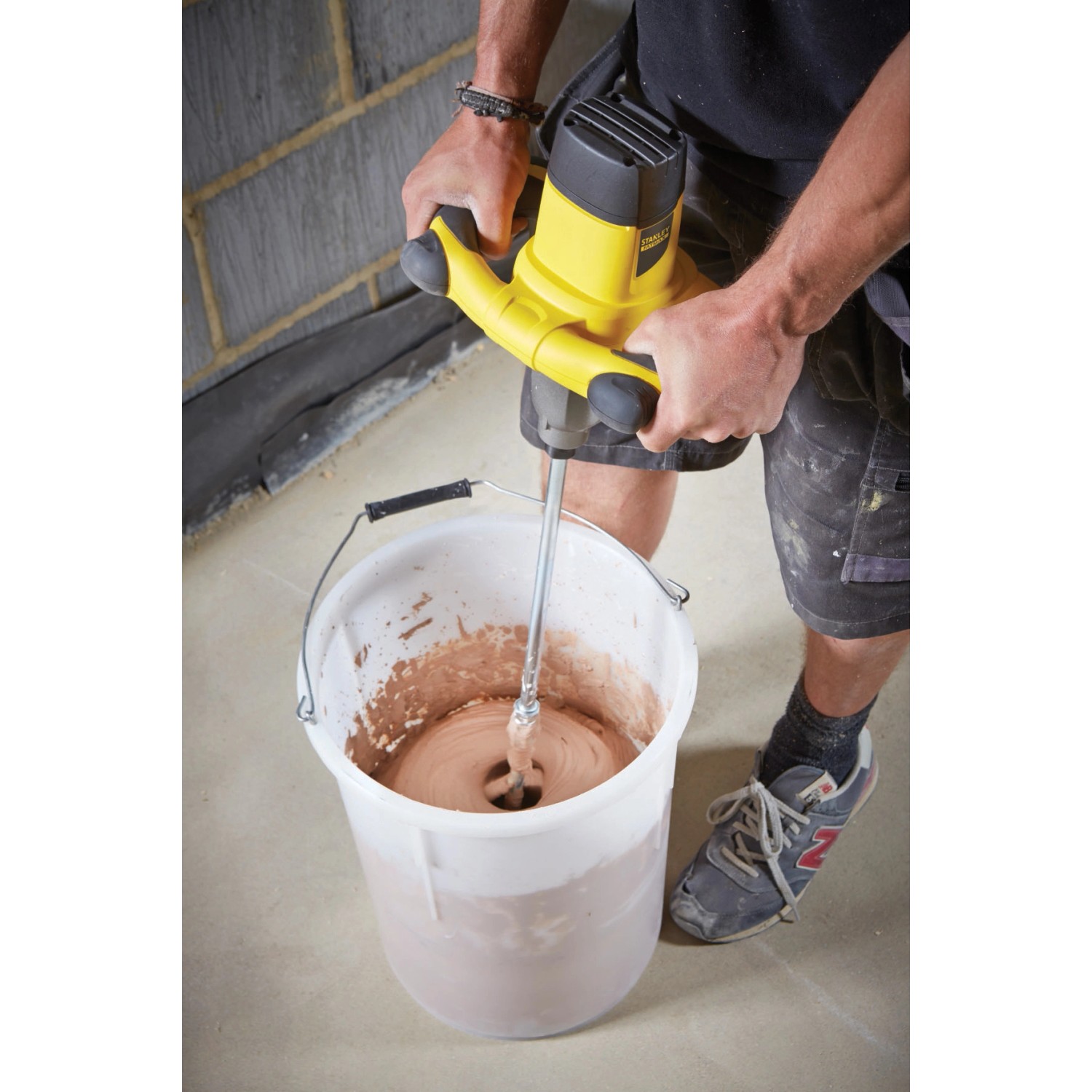 Stanley FatMax Rührgerät FME190 beim Mischen von Mörtel im Eimer. Das Rührwerkzeug ist gelb und schwarz.