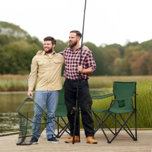 Zwei Männer mit grünem Sunula Campingstuhl, Angelrute und Kescher am See.