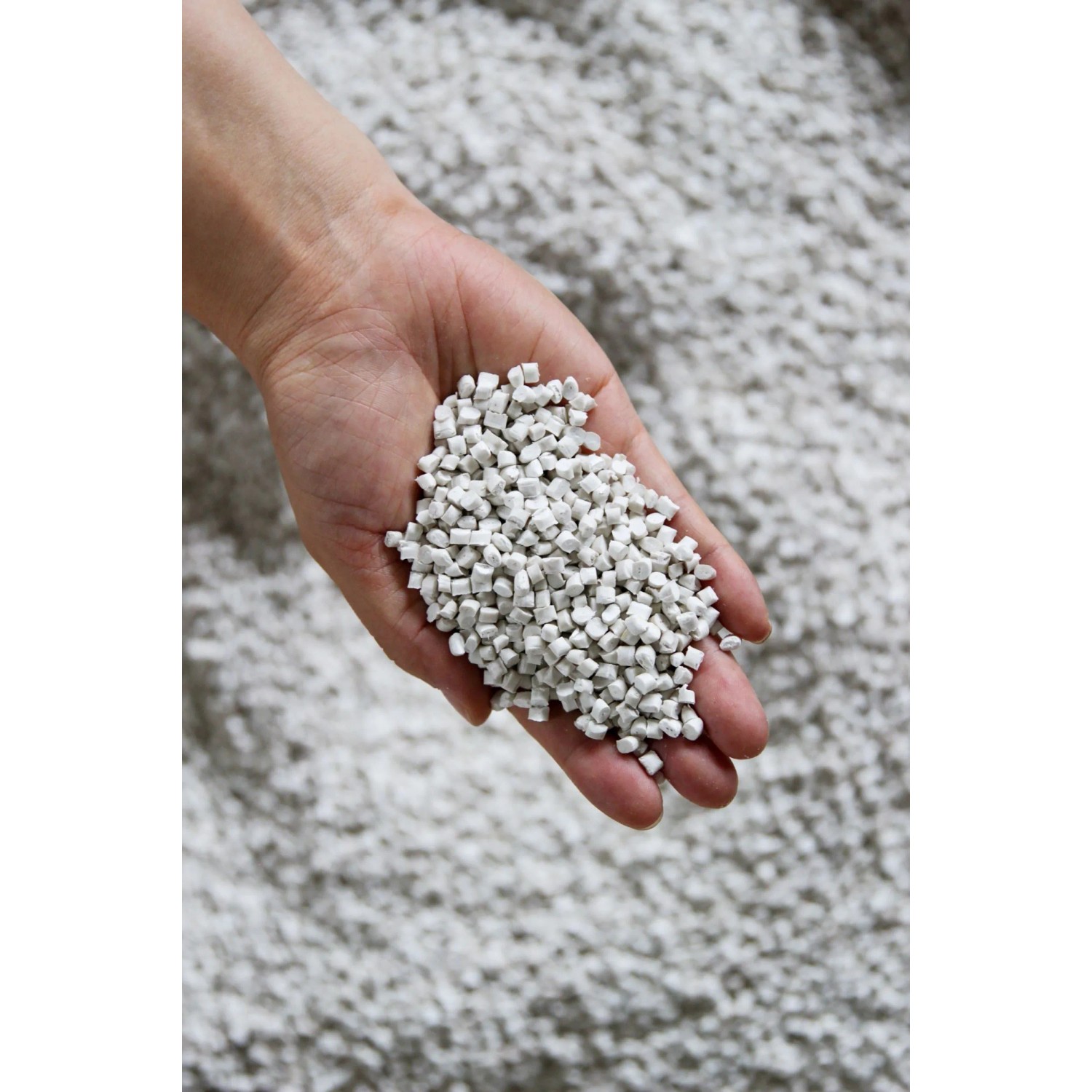 Hand hält Füllmaterial für Ecopots Amsterdam Pflanztöpfe, grau.