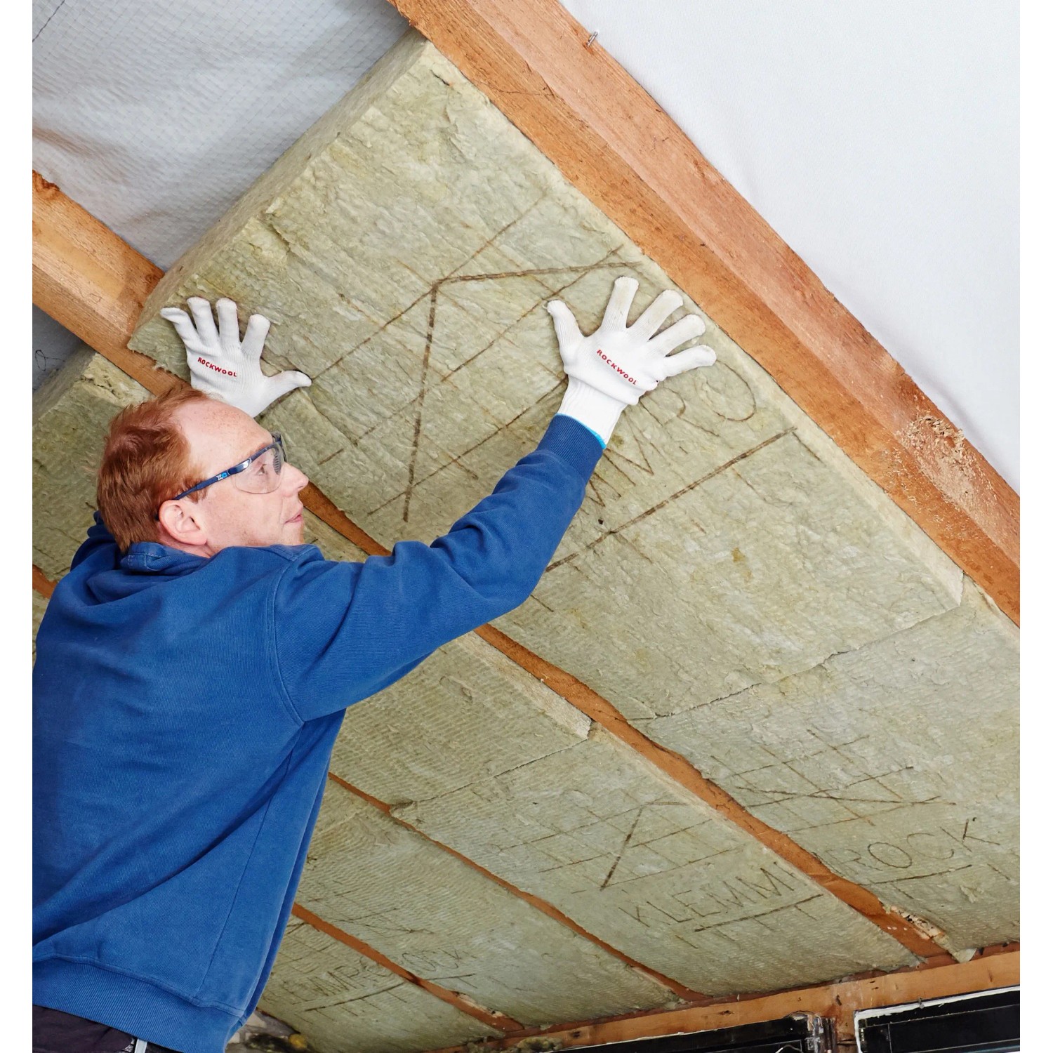 Mann montiert Rockwool Klemmrock Dämmwolle (120mm) zwischen Dachsparren.
