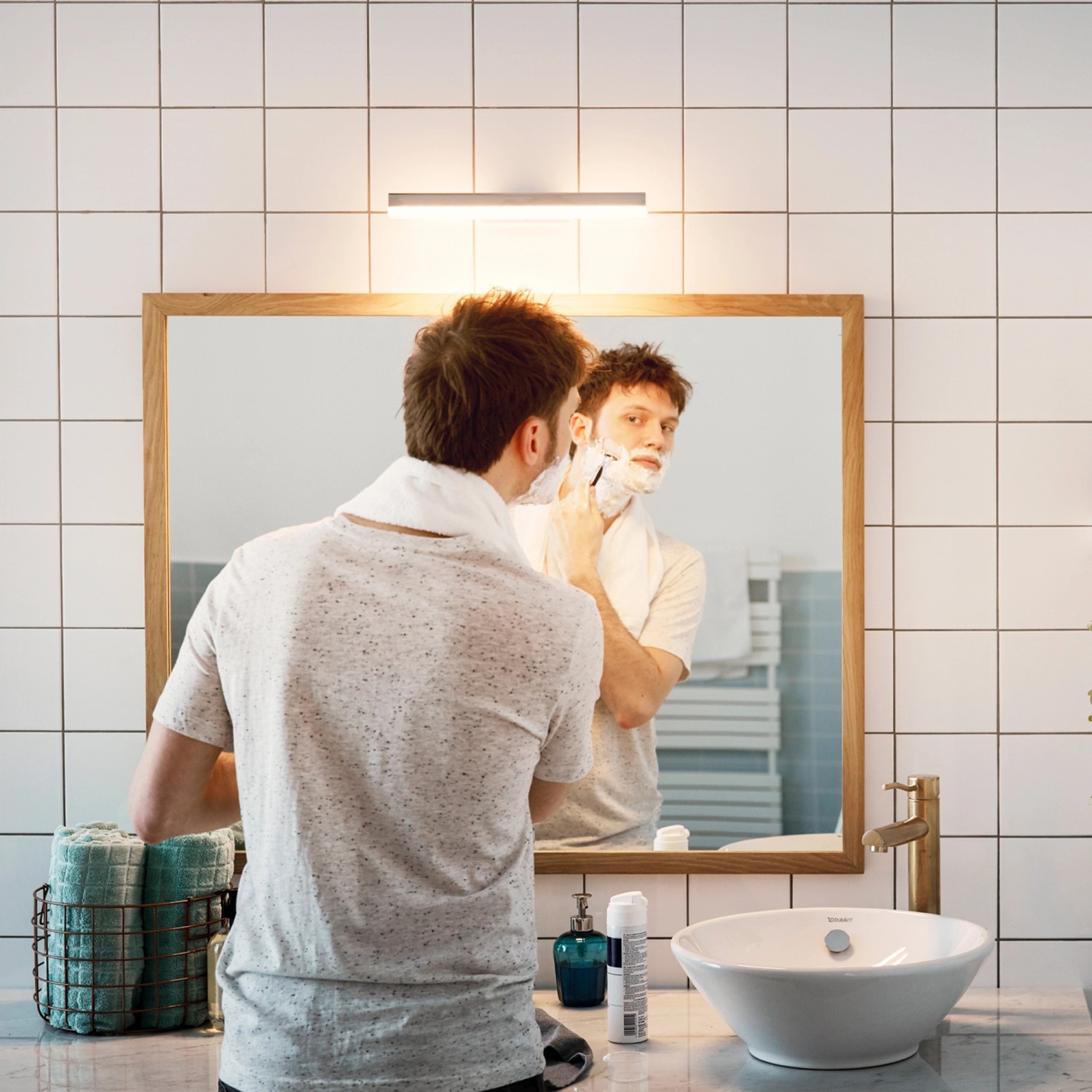 Mann rasiert sich unter einer Philips LED-Leuchtstofflampe im Bad.