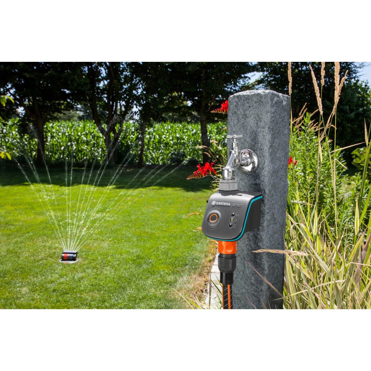 Gardena smart Water Control Bewässerungscomputer am Wasserhahn mit Rasensprenger im Garten.
