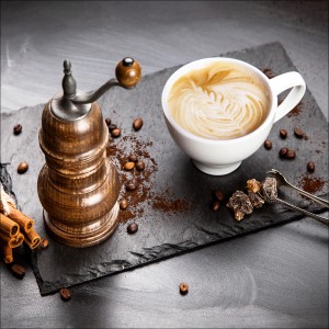 Glasbild Café: Tasse Cappuccino, Kaffeemühle, Bohnen und Zimtstangen auf Schieferplatte, 20x20 cm.