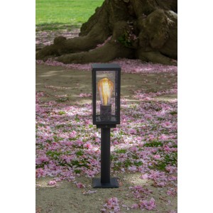 Schwarze Eco-Light Sockelleuchte Karo mit Dämmerungssensor im Garten mit rosa Blüten.