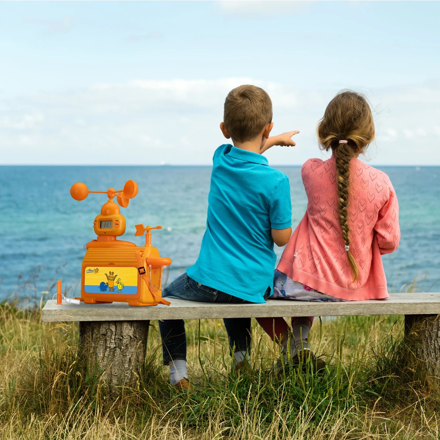 DieMaus Wetterstation für Kinder mit Zubehör auf Bank vor Meer, zwei Kinder schauen aufs Meer.