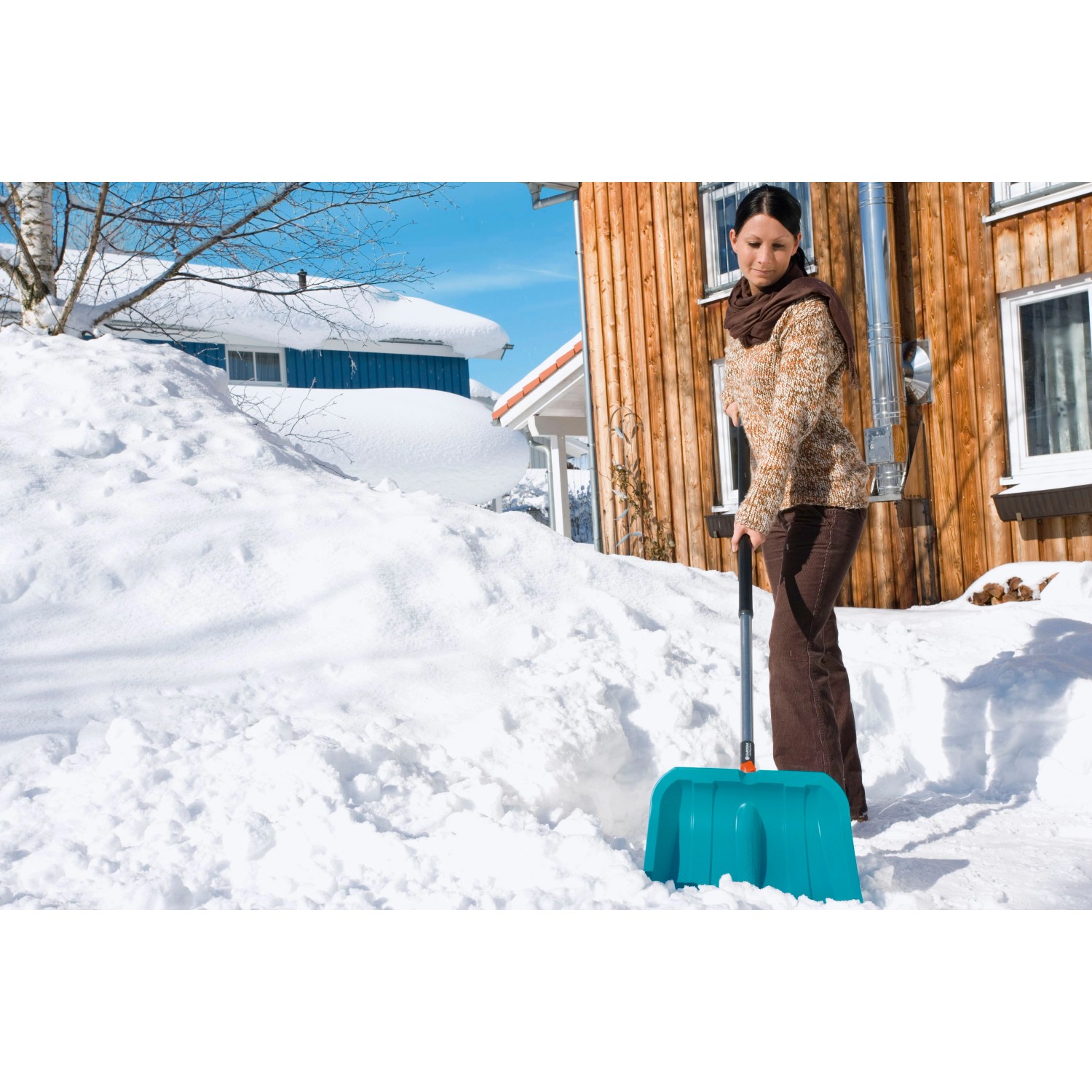Frau schiebt Schnee mit dem Gardena combisystem Schneeschieber ES 40 cm.