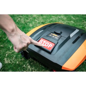 Hand drückt Stopptaste am Yard Force EasyMow 260B Mähroboter auf Rasen.