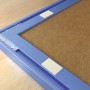 Nahaufnahme: Blauer Bilderrahmen mit Fischer Montage Streifen zur Befestigung.