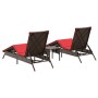 2 braune Poly Rattan Sonnenliegen mit roter Auflage und kleinem Tisch für den Garten.