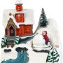 Beleuchtetes Weihnachtsdorf mit roter Kirche, Schnee und Figur, die Schneemann baut. Mehrfarbige Weihnachtsdekoration.