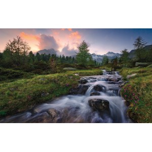 Vlies Fototapete Wild Paradise: Bachlauf in grüner Landschaft mit Bergen im Hintergrund.