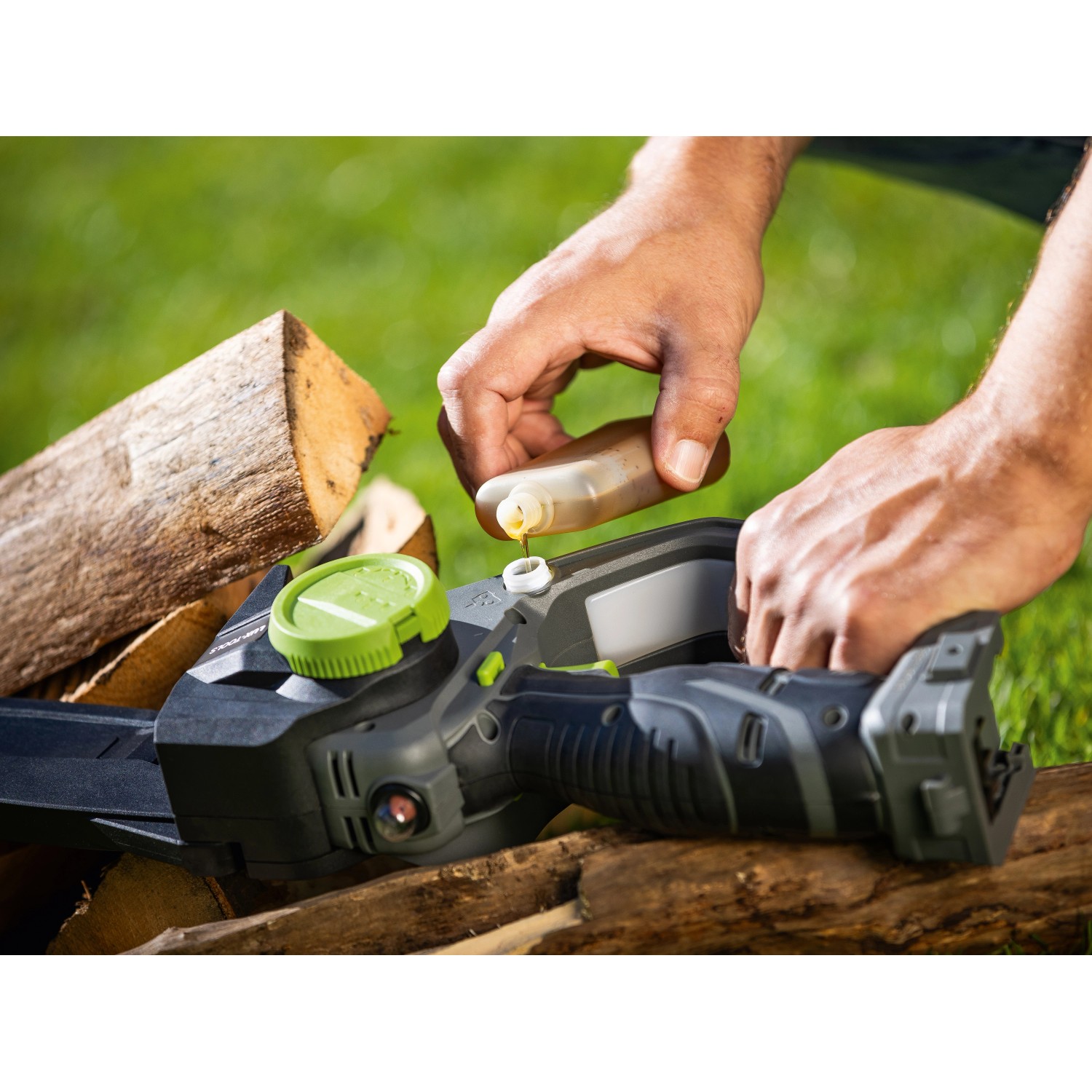 LUX-TOOLS Akku-Astsäge: Person ölt Kette der Akku-Kettensäge. Holzscheite im Hintergrund.