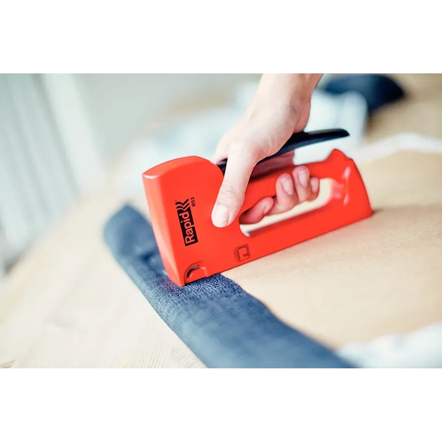 Roter Rapid Handtacker R53 beim Tackern von Stoff auf Holz, geeignet für Klammern Typ 53.