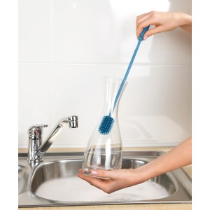 Wenko Silikon Flaschenbürste in Blau reinigt eine Karaffe in der Spüle.
