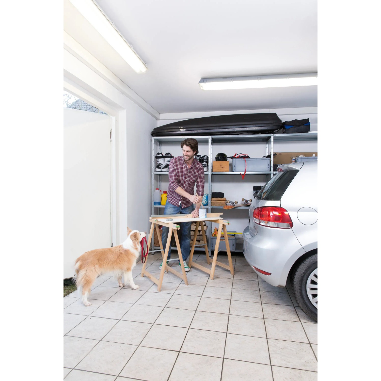 Mann arbeitet in Garage mit Ledvance LED-Feuchtraumleuchte. Helles, kaltweißes Licht.