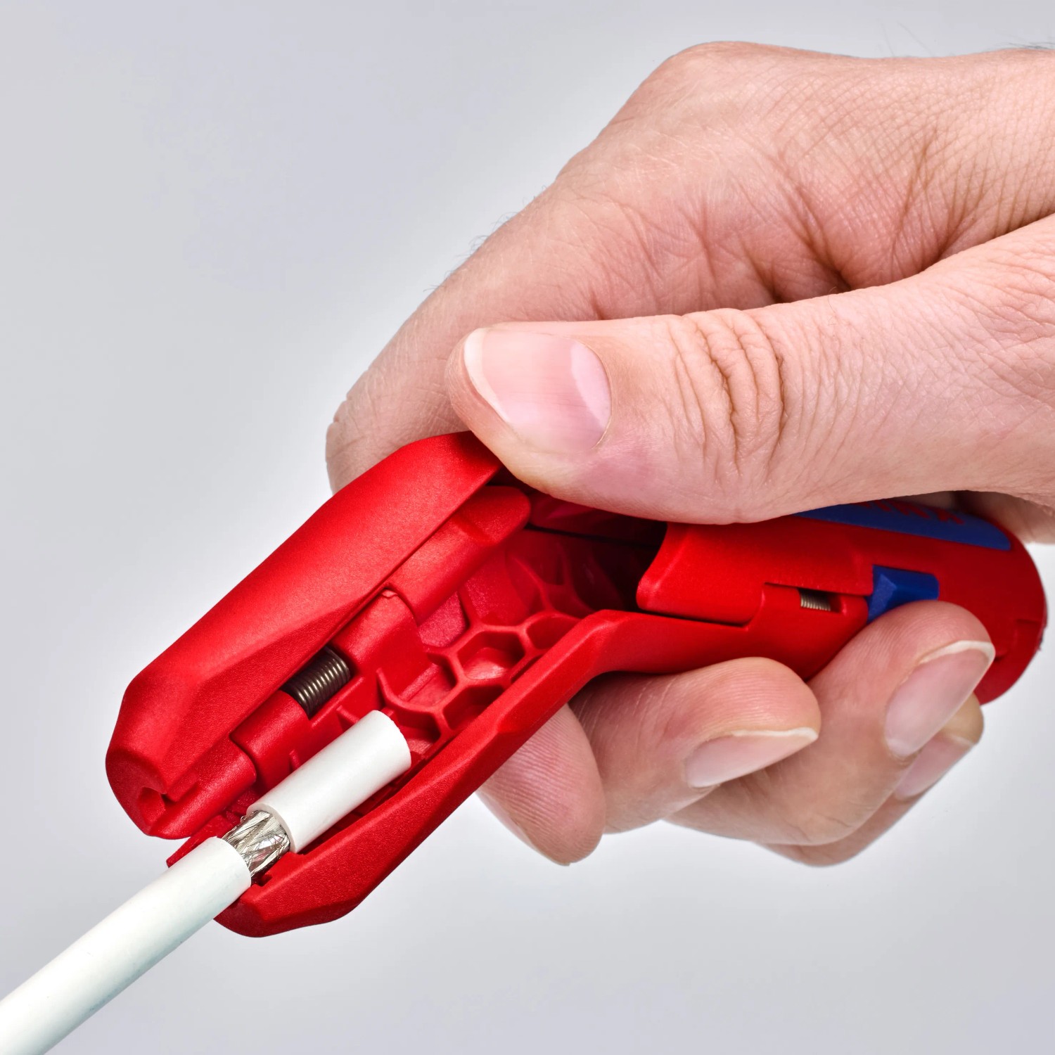 Knipex ErgoStrip Abmantelwerkzeug in roter Farbe beim Abisolieren eines Kabels.