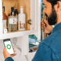 Mann öffnet weißen Schrank mit Yale Smart Cabinet Lock per App auf dem Smartphone.