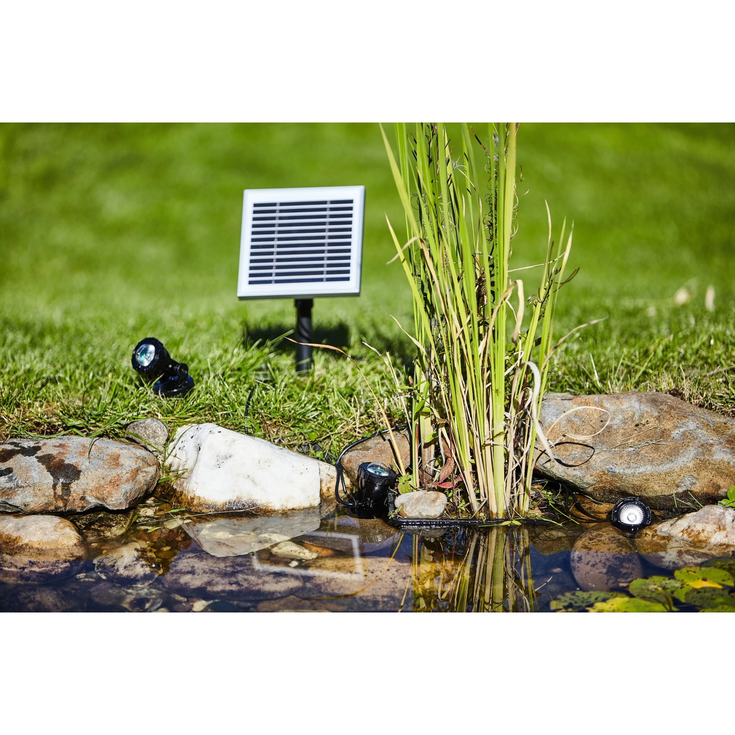 Heissner Solar Teichbeleuchtung Set mit 3 LED-Spots, Solarpanel und Erdspießen am Gartenteich.