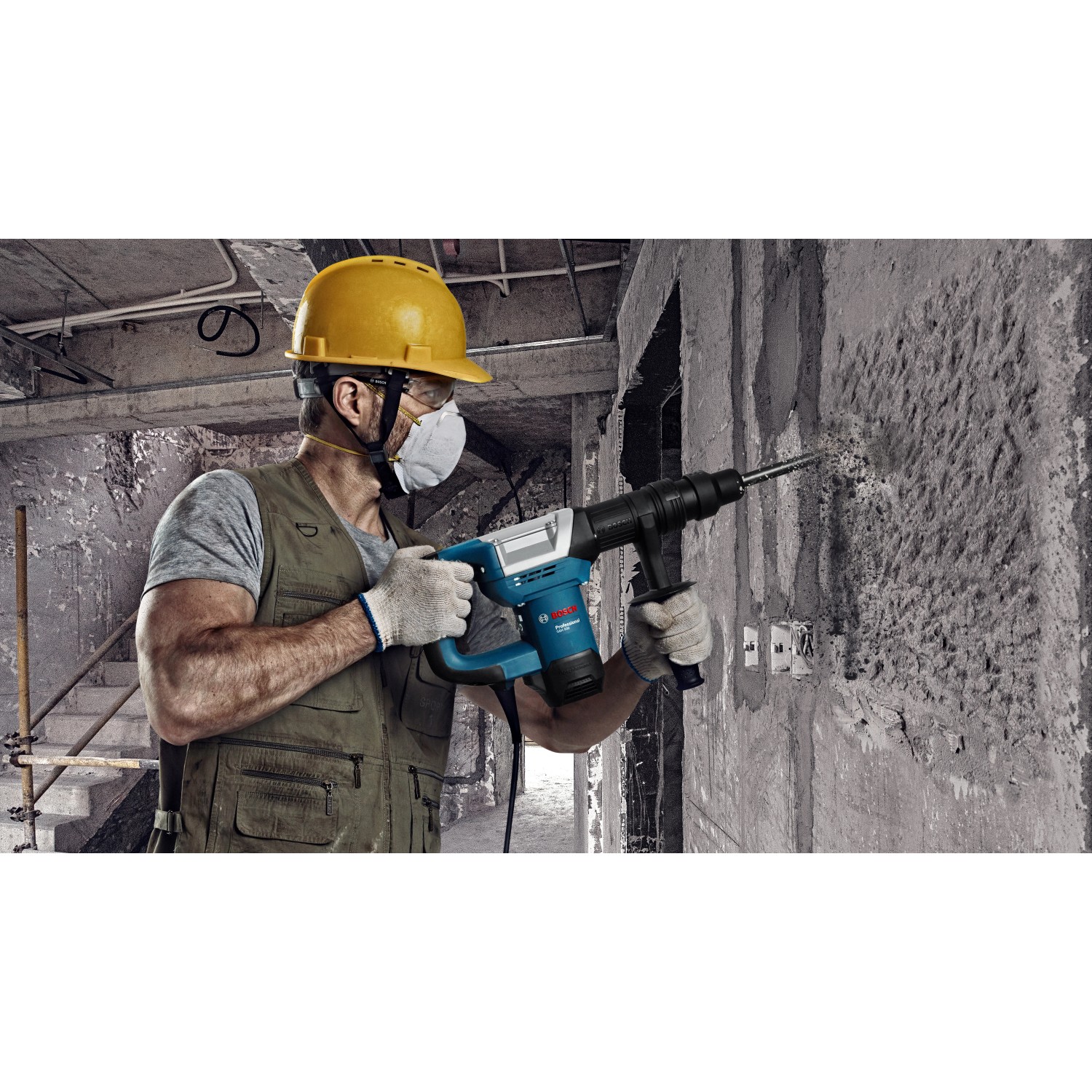Handwerker bohrt mit blauem Bosch Professional Bohrhammer GSH 5 CC ein Loch in eine Betonwand.