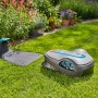 Gardena smart Sileno life Mähroboter Set mit Ladestation auf Rasen vor Blumenbeet.