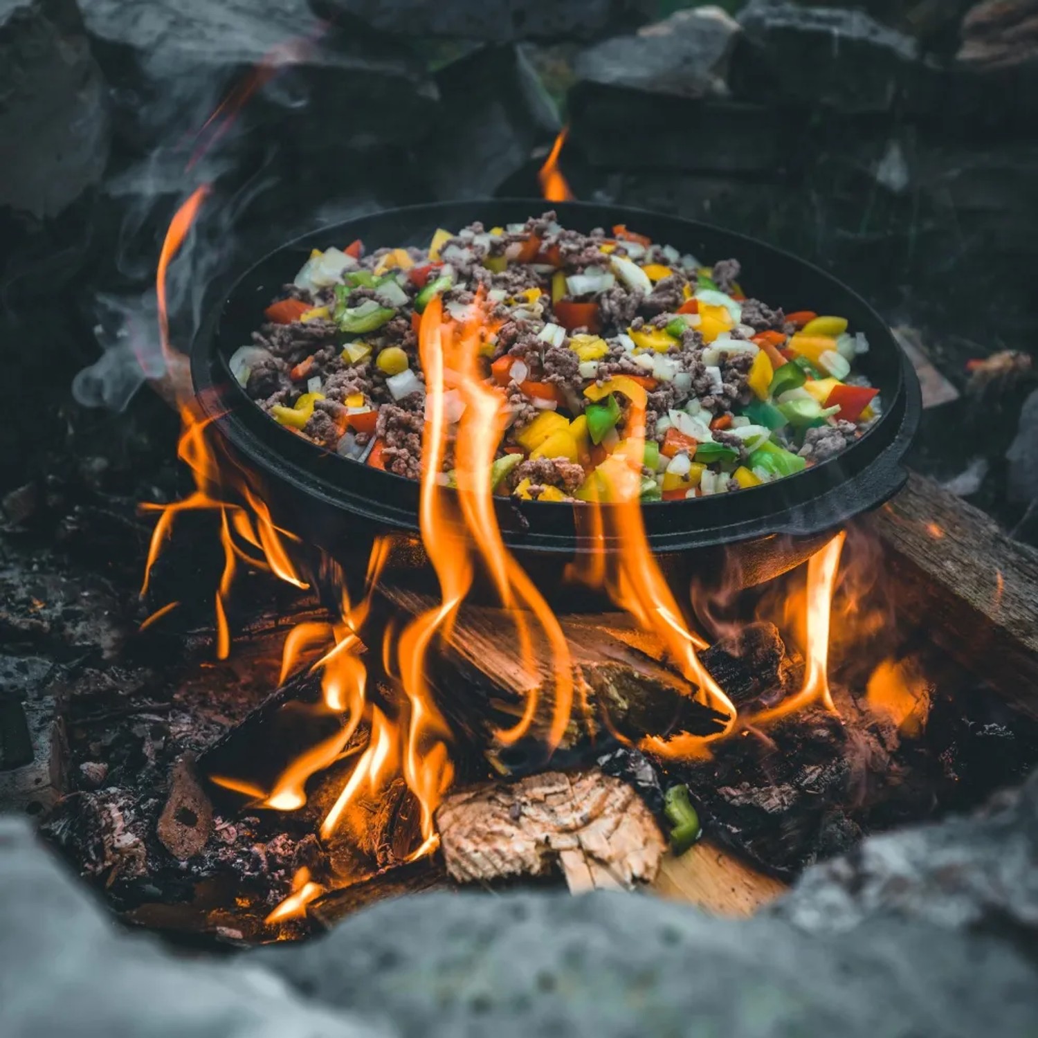 Petromax Dutch Oven FT4.5-T auf offenem Feuer mit Gemüse und Fleisch. Grillutensil für Outdoor-Küche.
