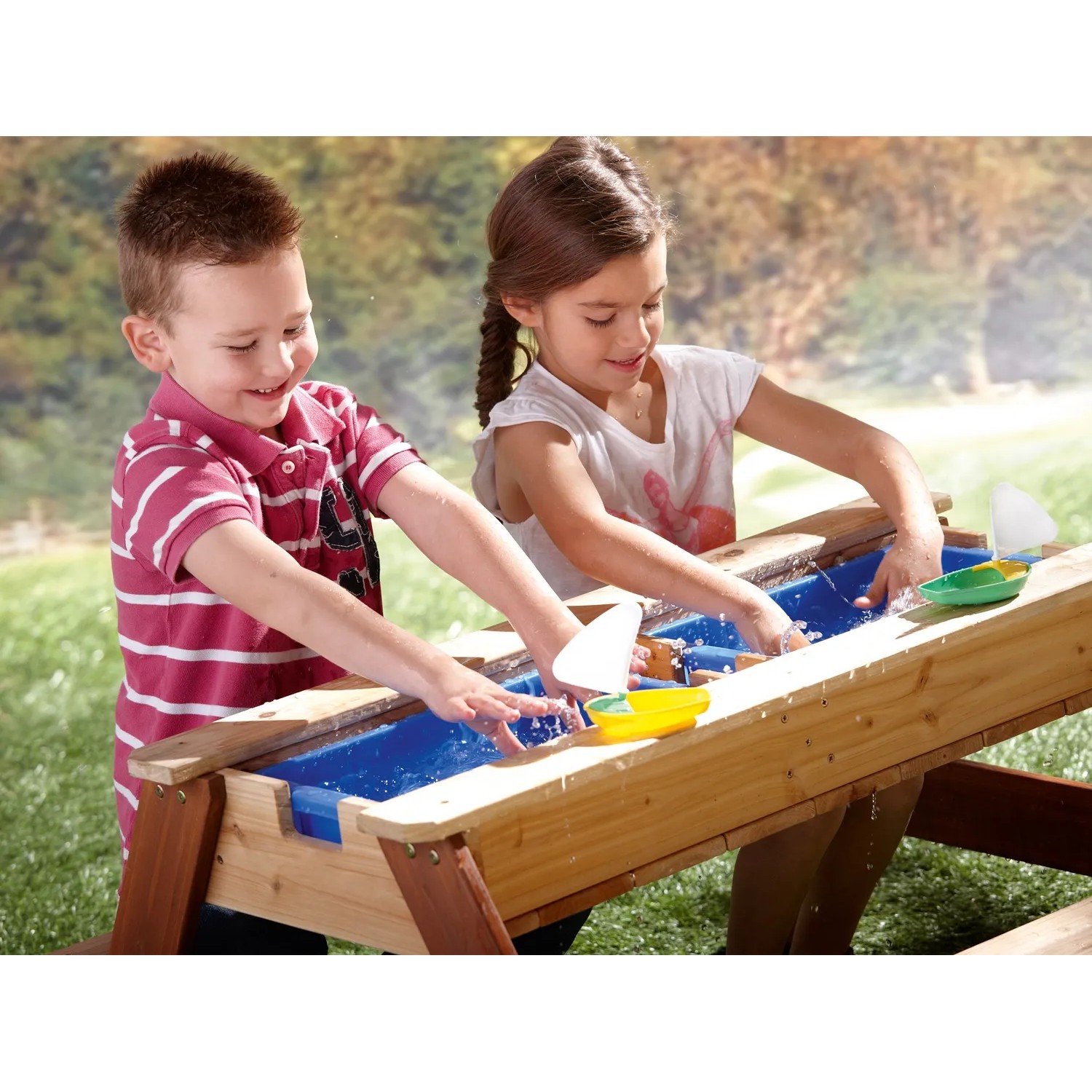 Axi Sand- und Wasser-Picknicktisch Nick mit zwei Kindern beim Spielen mit Booten.