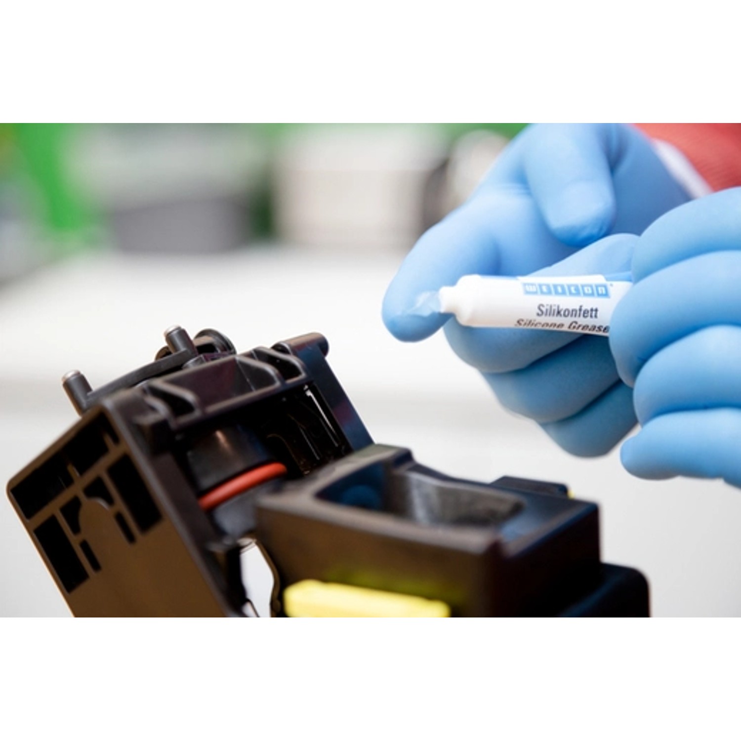 Anwendung von WEICON Silikonfett (5g Tube) auf ein Maschinenteil. Schmierstoff für Ventile und Dichtungen.