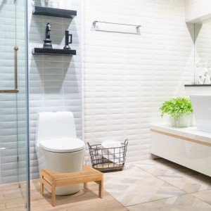 Natürlicher Bambus Toilettenhocker vor weißem WC. Rutschfester Badhelfer für eine gesunde Hocksitzhaltung im Badezimmer.