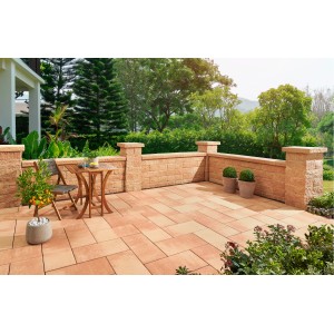 Bruchsteinmauer mit Pfeilerelementen in Sandsteinoptik, Teil einer Gartengestaltung mit Sitzbereich.