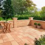 Bruchsteinmauer mit Pfeilerelementen in Sandsteinoptik, Teil einer Gartengestaltung mit Sitzbereich.