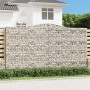 Hoher Gabionen-Sichtschutz mit Bogen, gefüllt mit Steinen, als dekorative Gartenmauer.