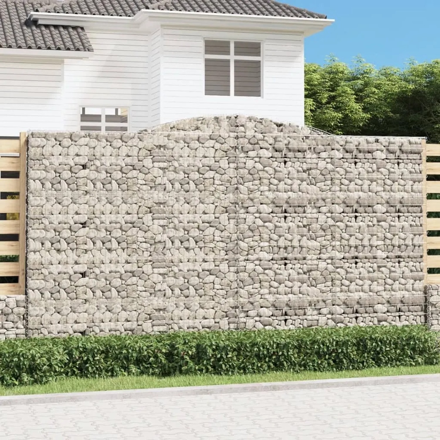 Hoher Gabionen-Sichtschutz mit Bogen, gefüllt mit Steinen, als dekorative Gartenmauer.