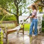 Frau reinigt Holzbank mit Kärcher Hochdruckreiniger K 7 Comfort Premium eco!Booster.