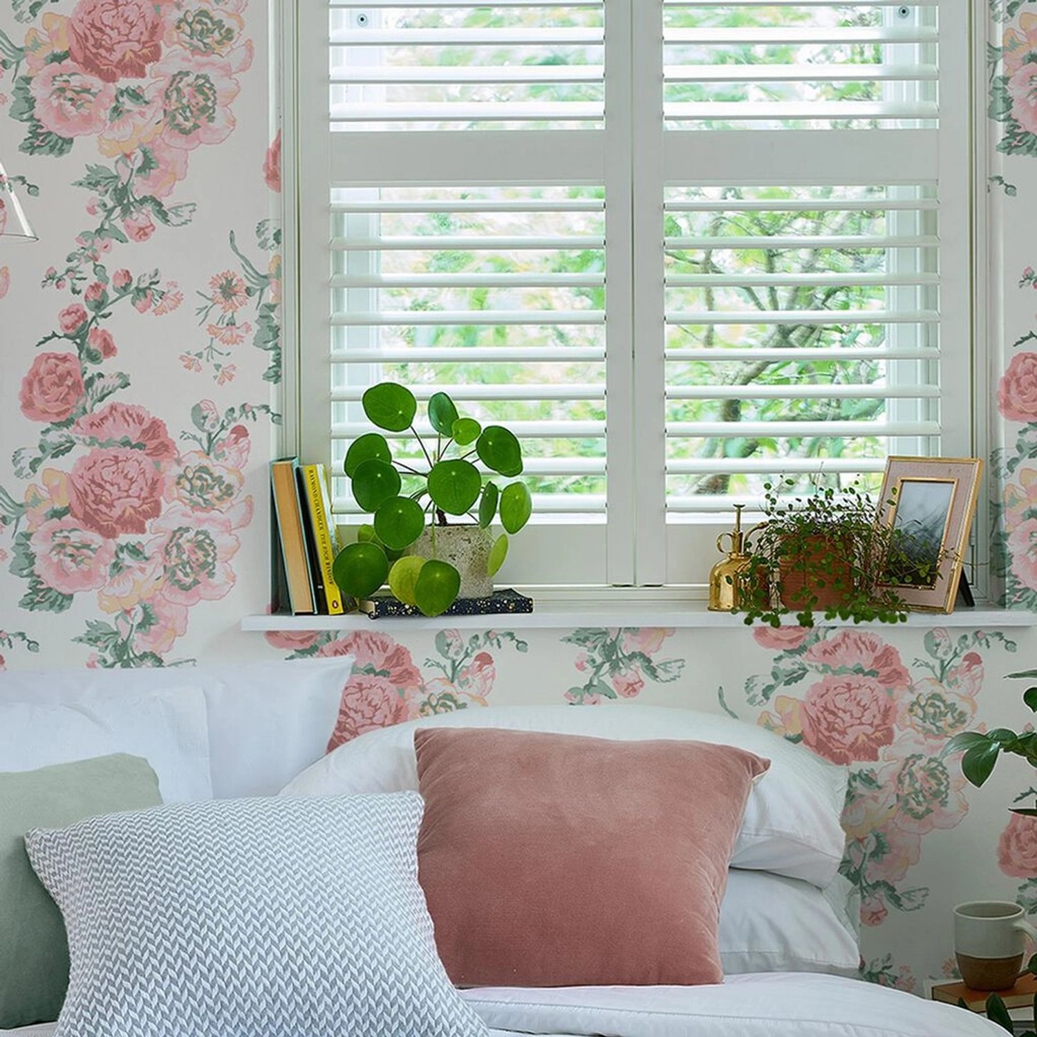 Laura Ashley Vliestapete Hollyhocks in Rosa/Koralle an Schlafzimmerwand mit Blumenmuster.