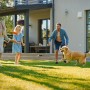 Familie spielt mit Hund auf Primaflor Kunstrasen Jazz Grün im Garten.
