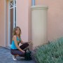 Garantia Regenwassertank 1000 l Sandbeige mit Frau und Gießkanne im Garten.