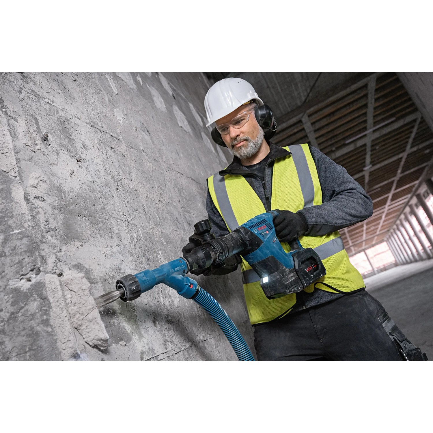 Handwerker mit Bosch Professional Akku-Schlaghammer GSH 18V-5 beim Stemmen einer Wand.