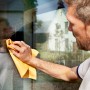 Mann reinigt Fenster mit gelbem Vileda Fenstertuch für streifenfreien Glanz.