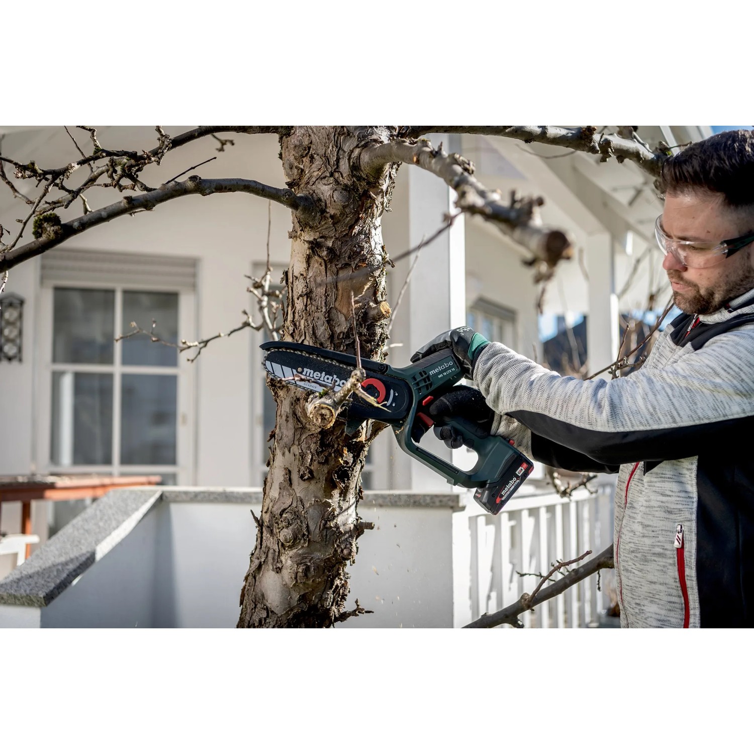 Mann schneidet Ast mit Metabo Akku-Gehölzsäge MS 18 LTX 15. Inkl. Akku, Ladegerät und Tasche.