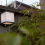 Anthrazitfarbene Lutec LED Solar Wandleuchte Doblo mit Bewegungsmelder an Holzwand.