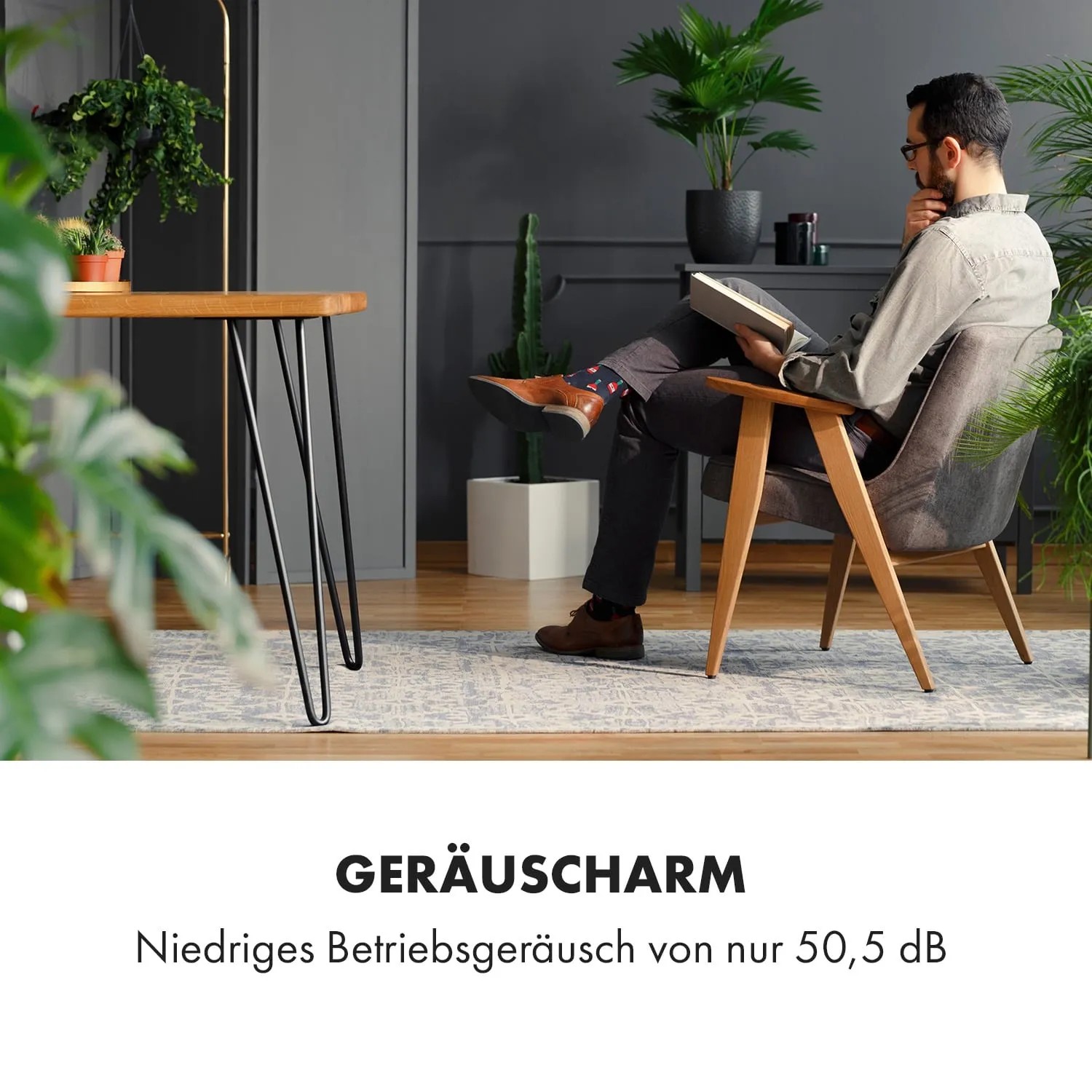 Mann liest in modernem Raum mit Klarstein Klimaanlage im Hintergrund.