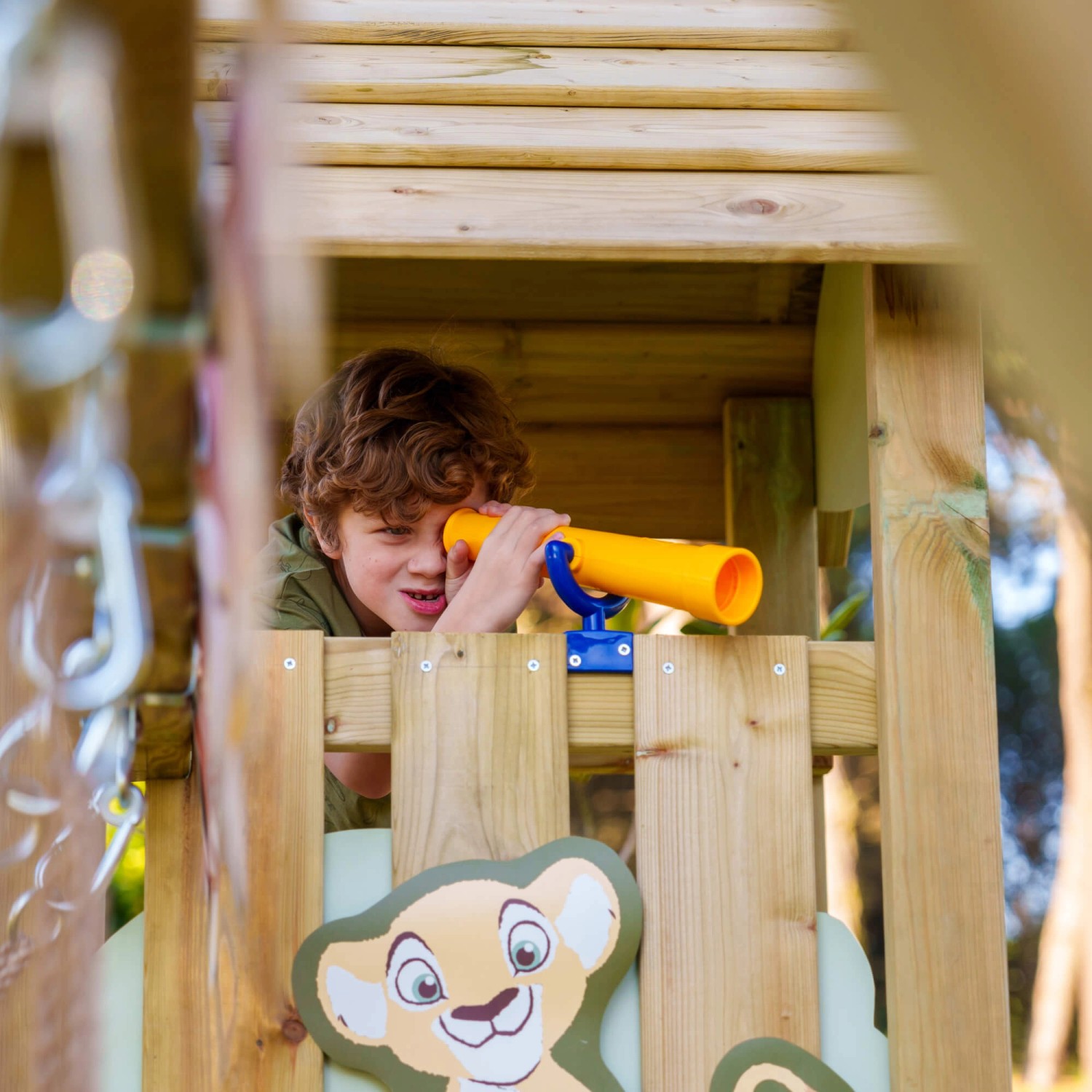 Kind im pastellgrünen Wickey Spielturm Disney Adventure mit gelbem Teleskop.