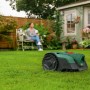 Bosch VISIMOW18V-100 Mähroboter auf Rasen, Frau im Hintergrund.