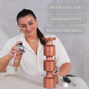 Frau sprüht mit belton Copper Metal Lackspray einen Deko-Kerzenständer an.