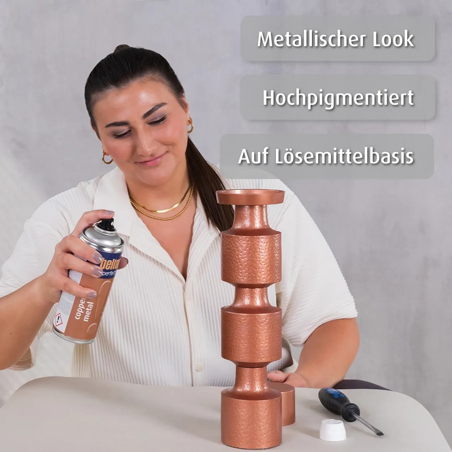 Frau sprüht mit belton Copper Metal Lackspray einen Deko-Kerzenständer an.
