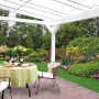 Freistehende, weiße Skan Holz Terrassenüberdachung Sanremo mit Sitzgruppe im Garten.