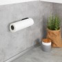 Wenko Küchenrollenhalter Nio, selbstklebend, schwarz, an grauer Wand mit Küchenrolle.