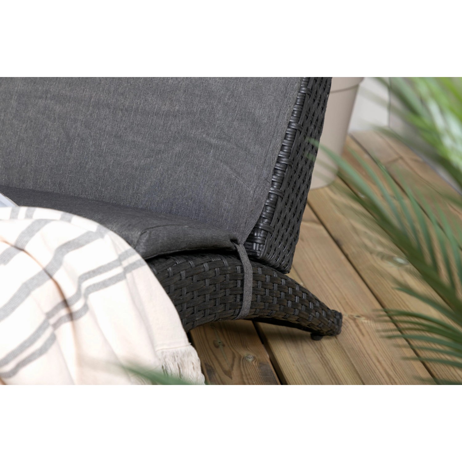 Detailansicht: Schwarze ebuy24 Archie Sonnenliege aus Rattan mit grauem Kissen.